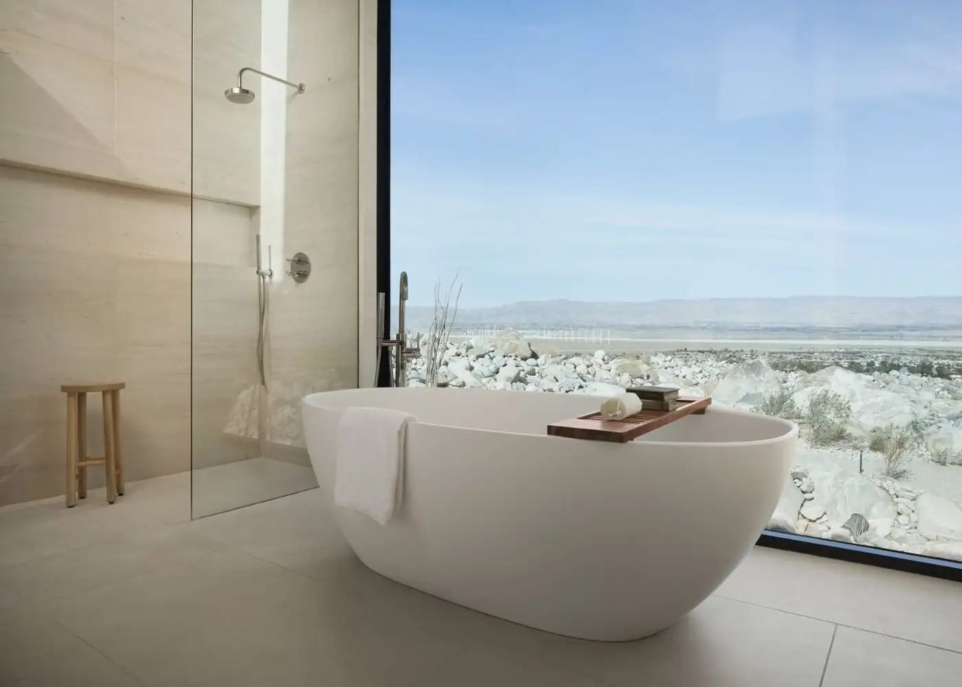 Frameless shower glass and a freestanding tub facing a desert window